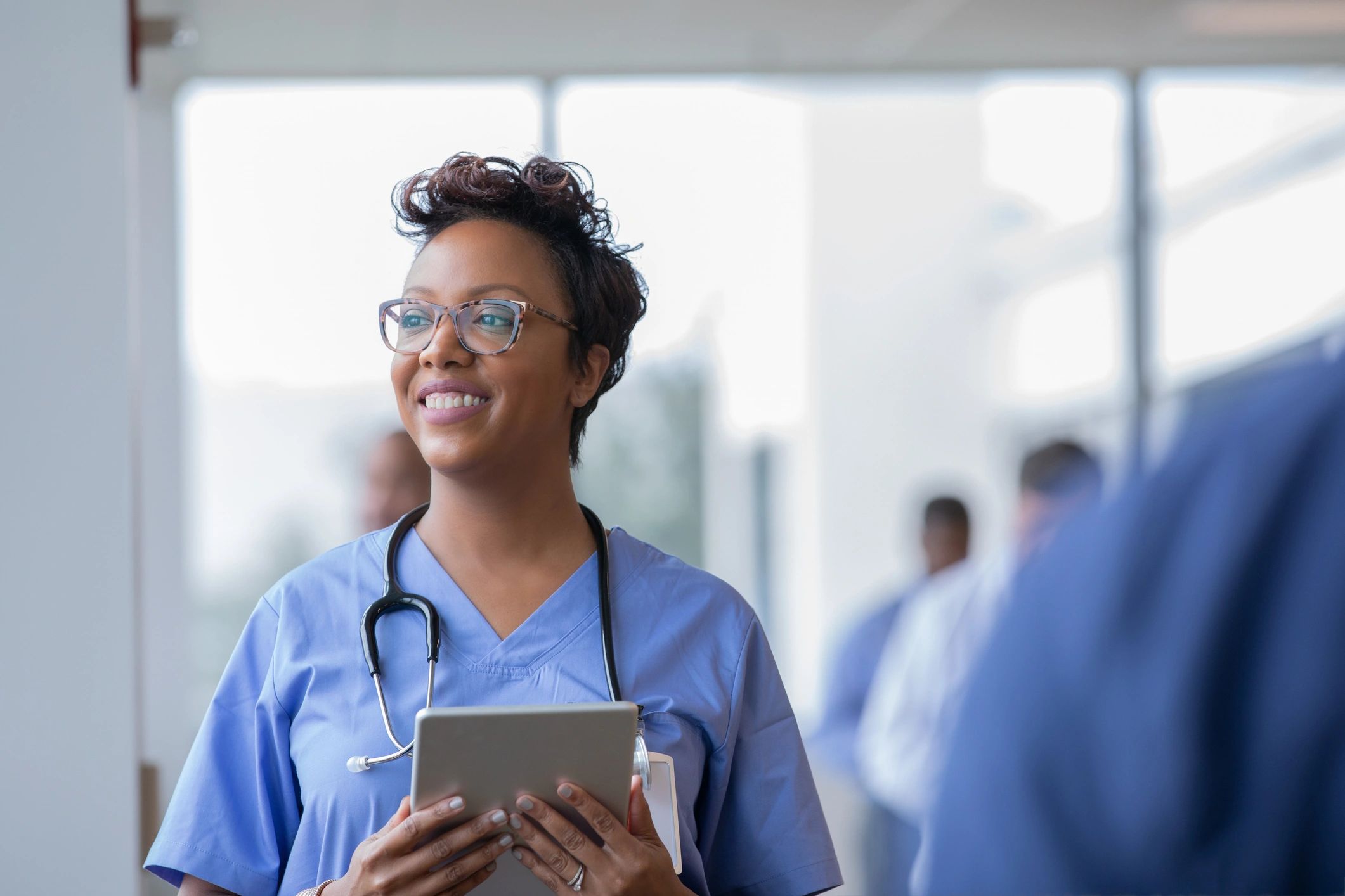 Clinician holding a tablet in a hospital hallway