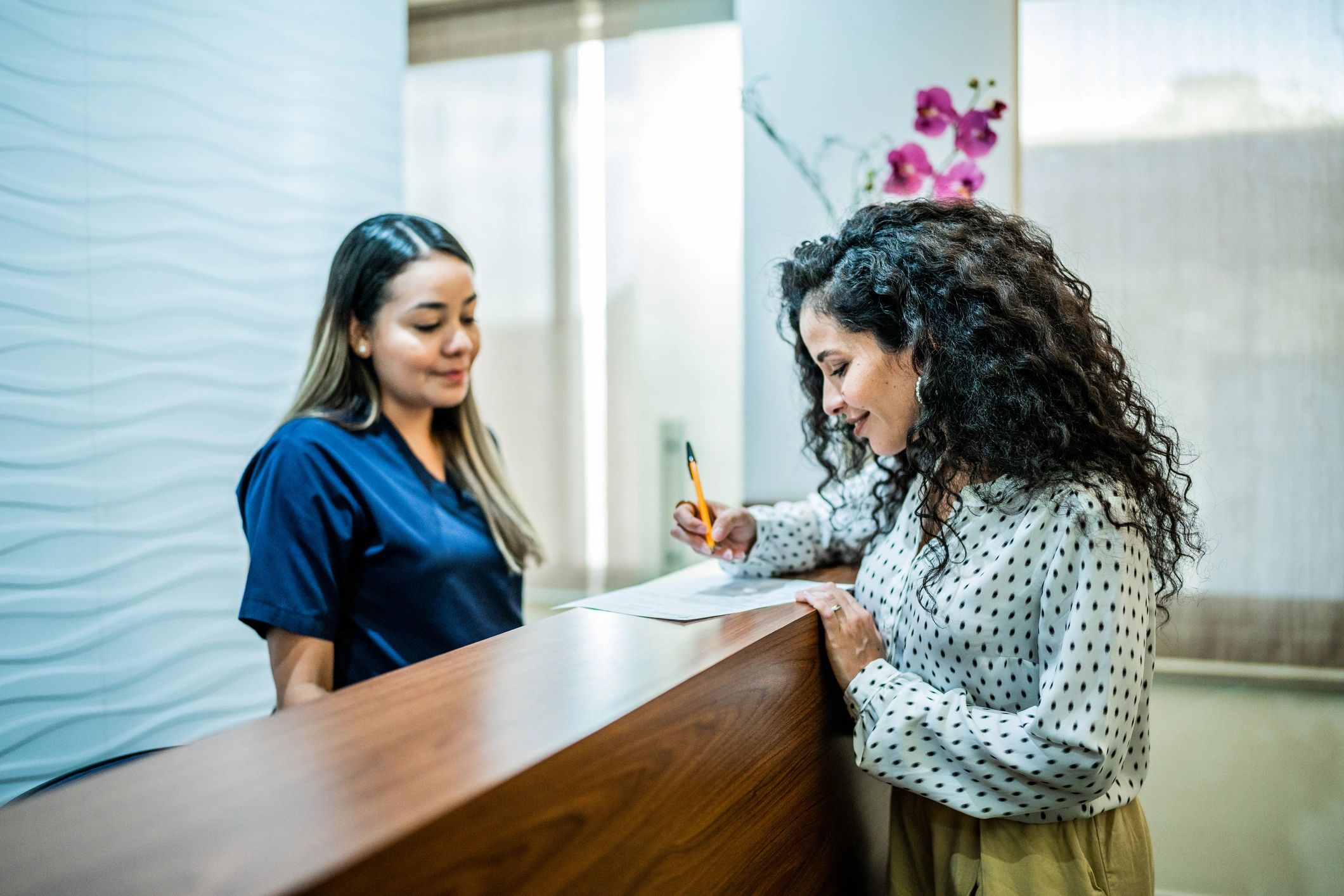 Patient speaking with receptionist at a medical office front desk