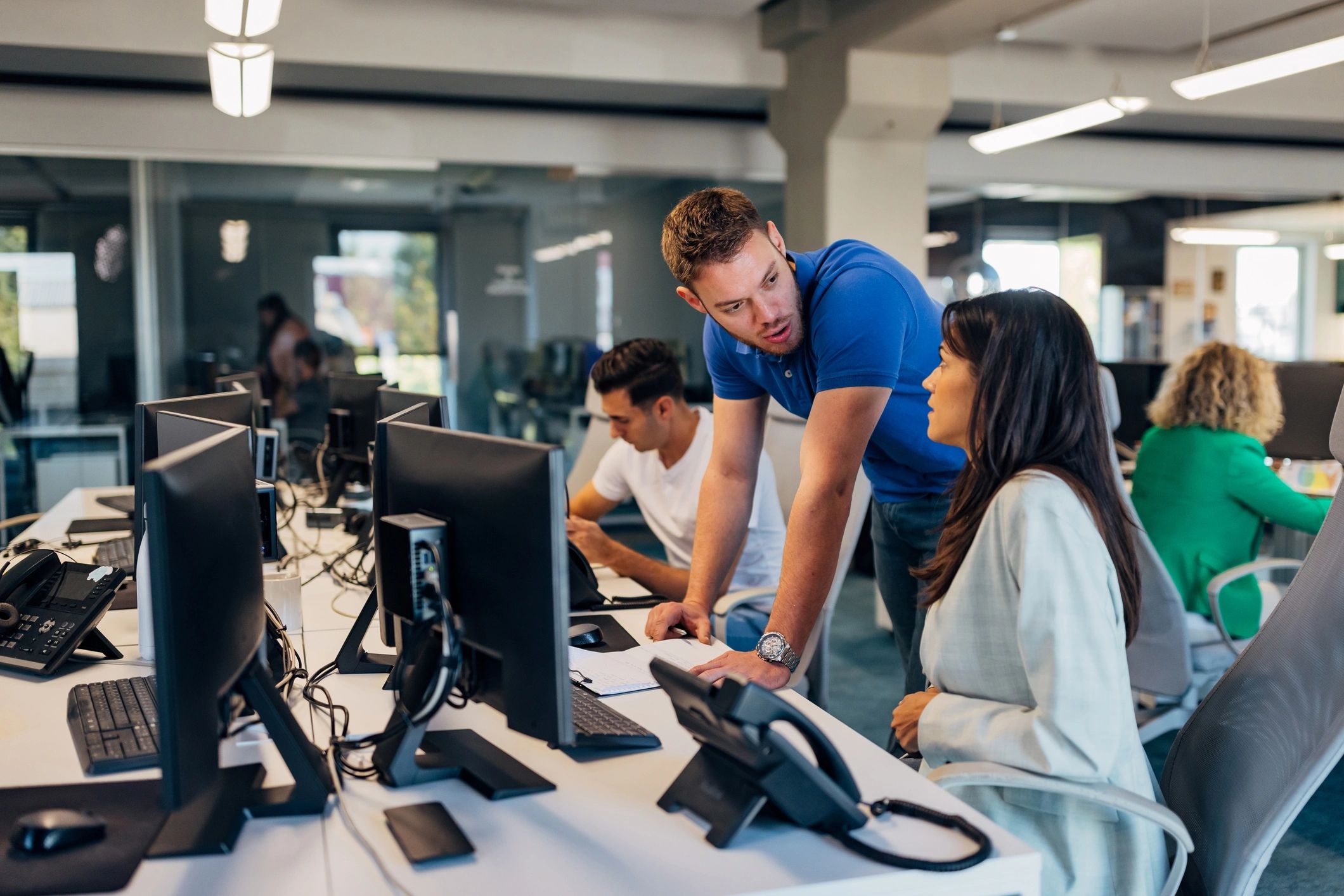 IT professional assisting a colleague at a computer