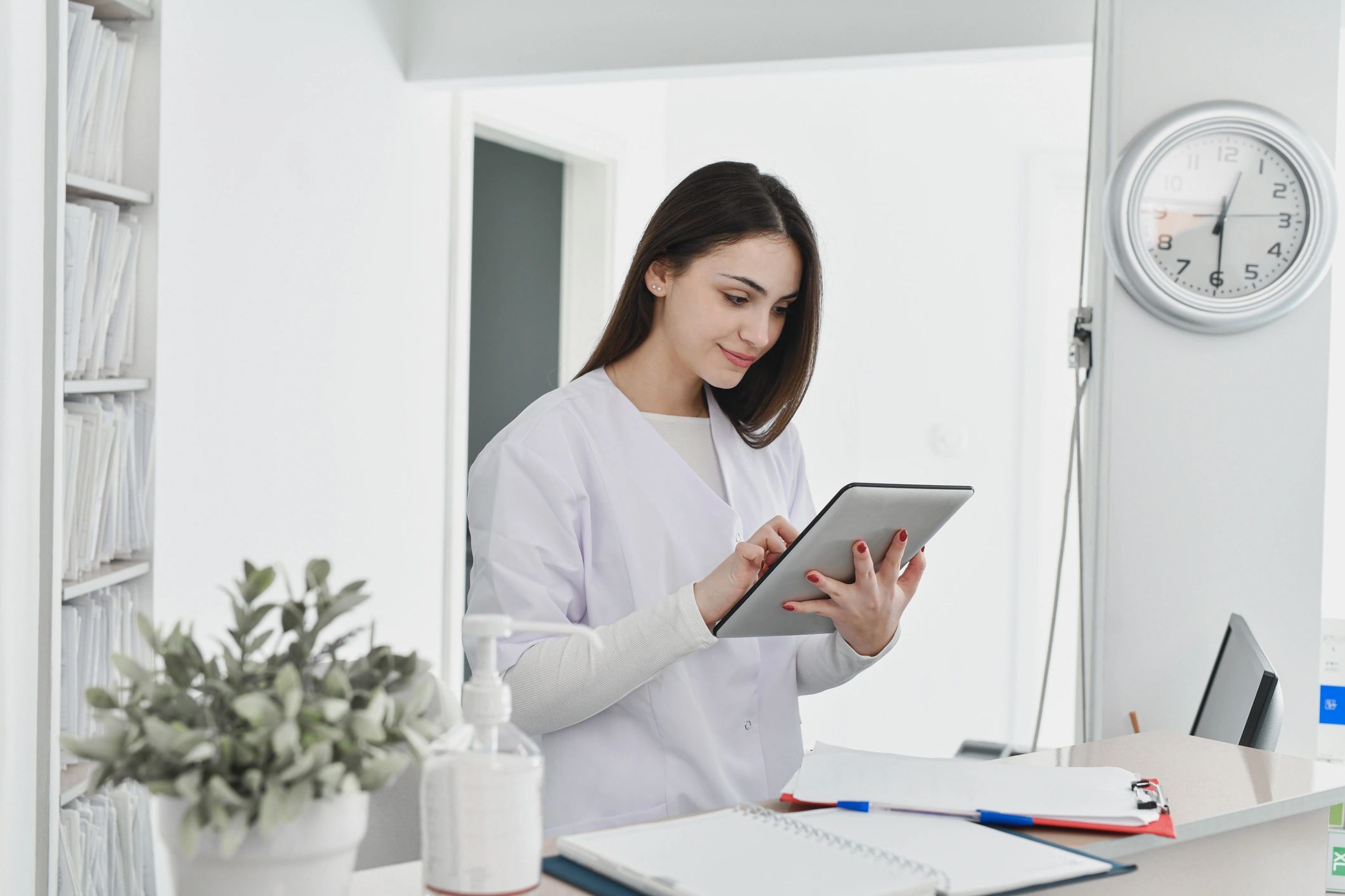 Nurse reviewing digital records on a tablet at a reception desk