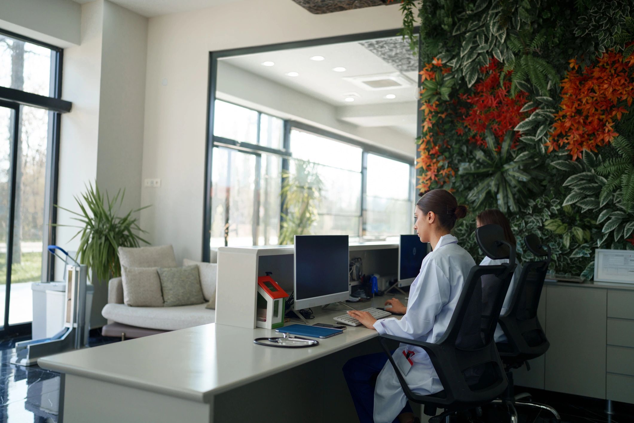 Two healthcare staff working at computers with IT support available